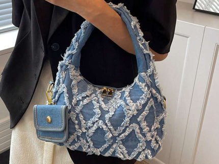 sac bleu brodee effilochee en jeans tenu par la main gauche femme elegante